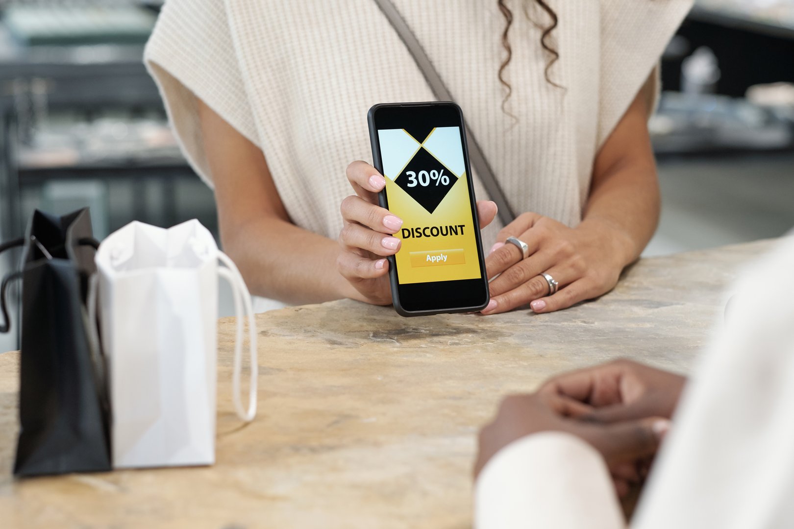 A customer presents a 30% discount code on their phone while purchasing products in a store.