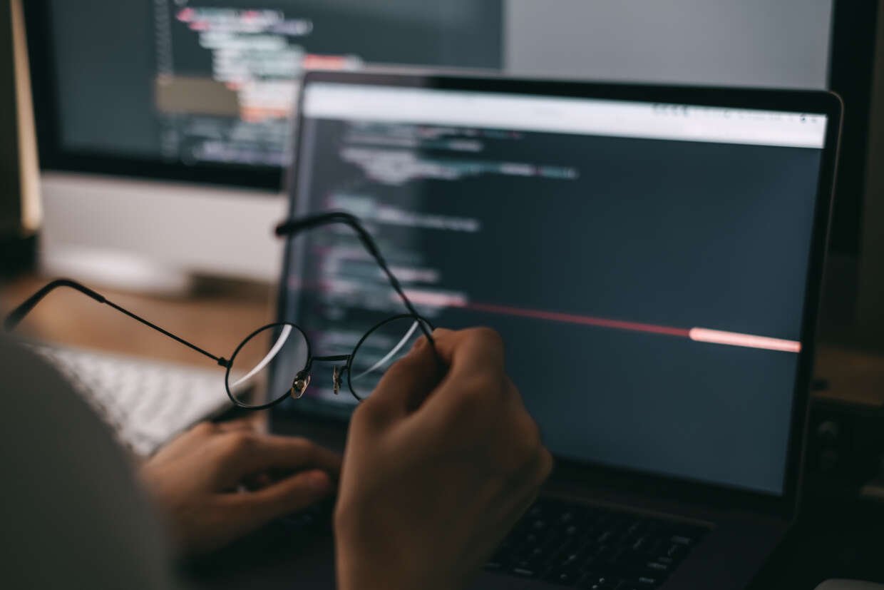 Website developer holding glasses coding