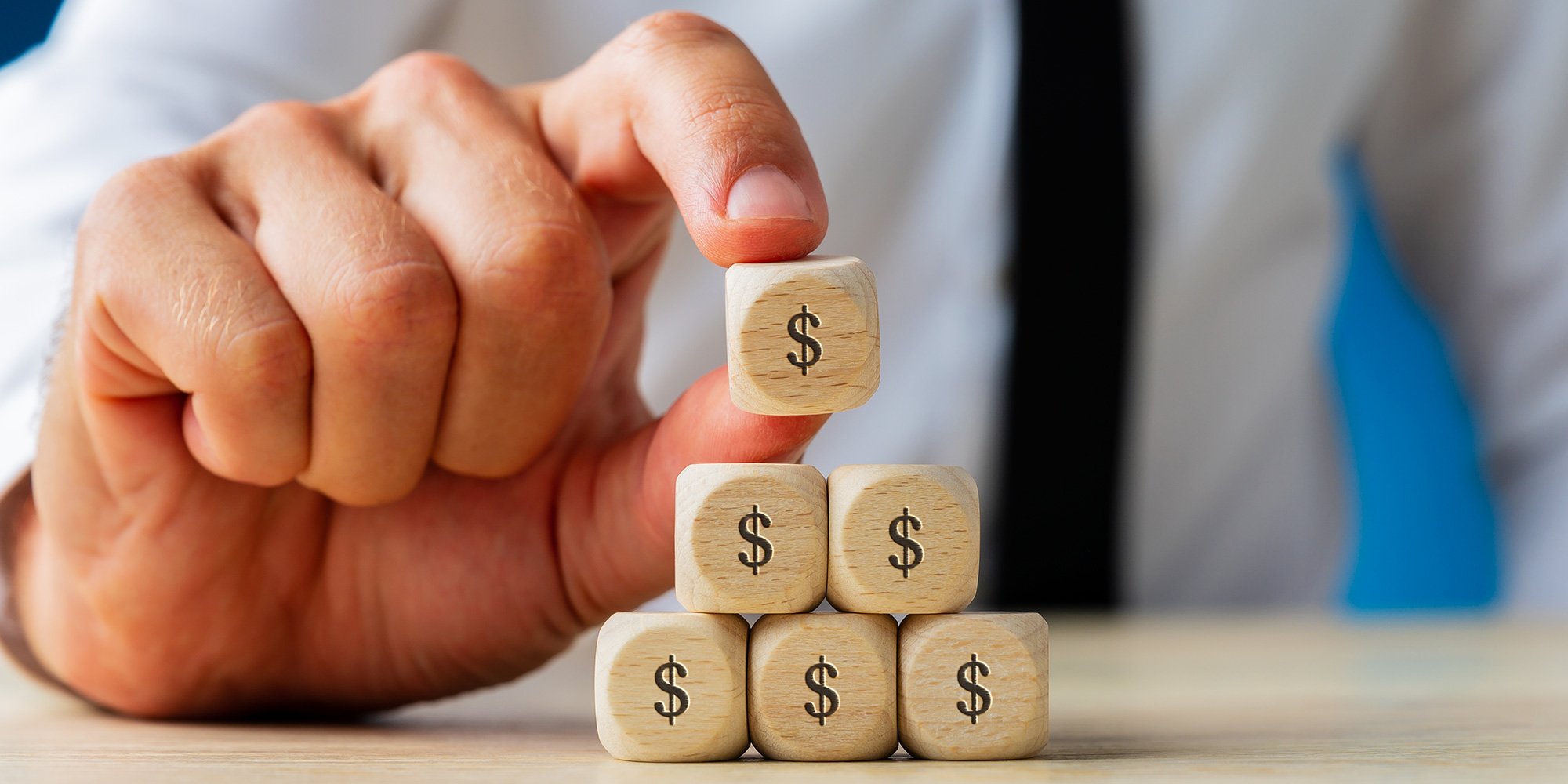 Business man stacks wooden dollar sign blocks conceptualising Conversion Rate Optimisation