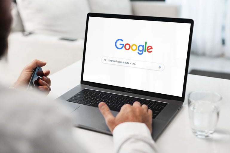 Businessman pauses to consider search intent on Google search screen on laptop