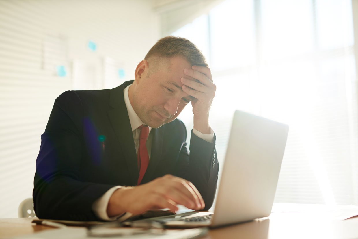 Man with hands on head looks at low organic CTR data on laptop thinking of how to improve it