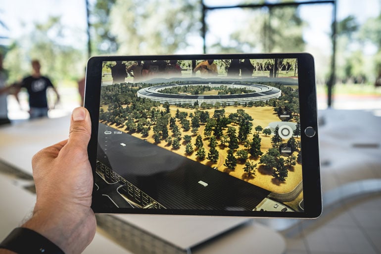 A man taking an image of a model building on an iPad.