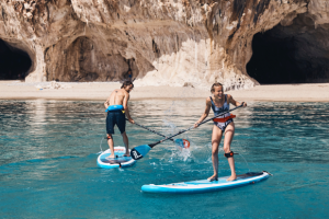 Girl & Boy Splashing eachother with water whilst Paddle Boarding 