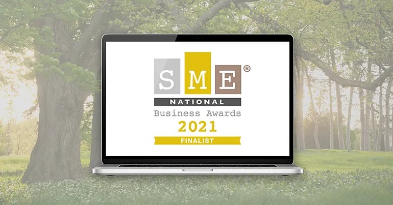 Innovation Visual's SME National Business Awards 2021 Finalist Badge for 'Positive Impact' on laptop screen in front of green environment