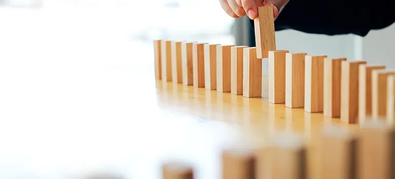 business man aligns wooden block dominos