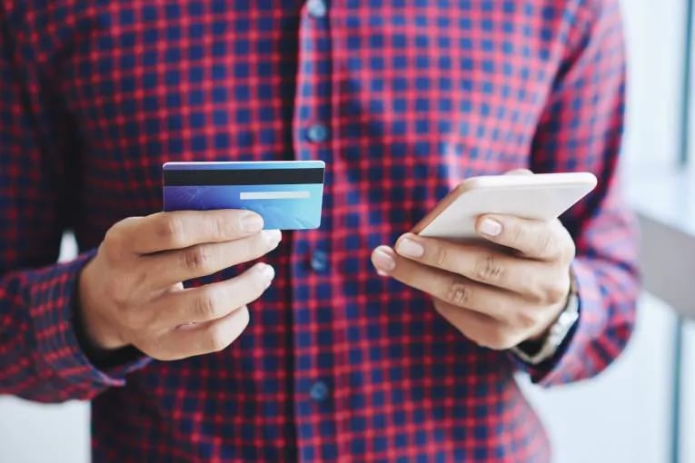 customer with card and phone poised to convert with payment 