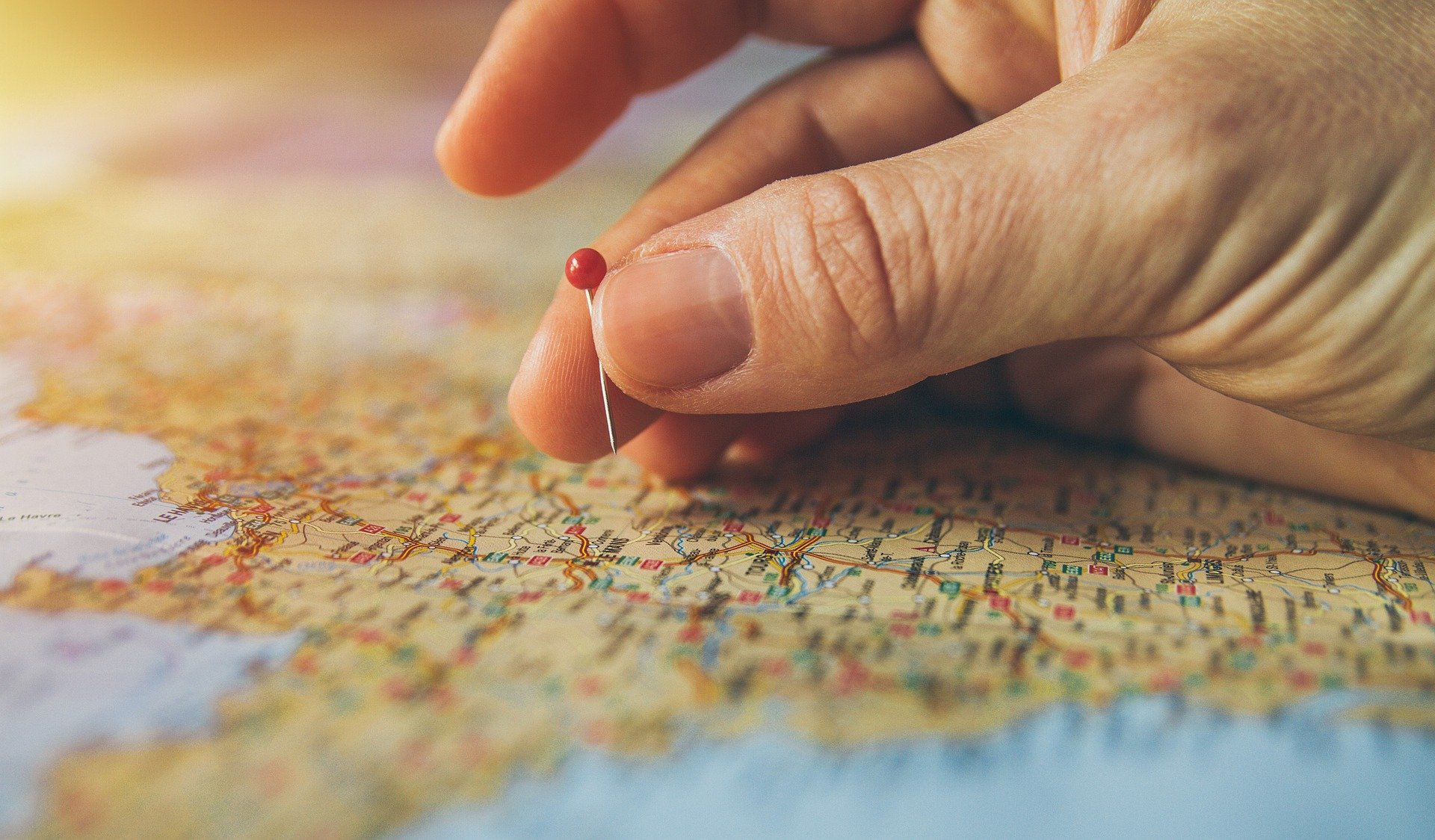 fingers holding a pin map of France