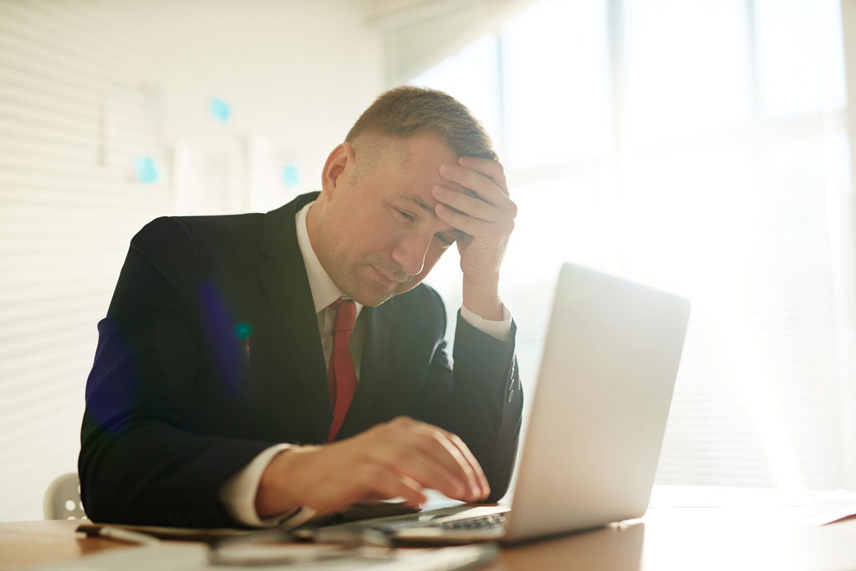 Man with hands on head looks at low organic CTR data on laptop thinking of how to improve it