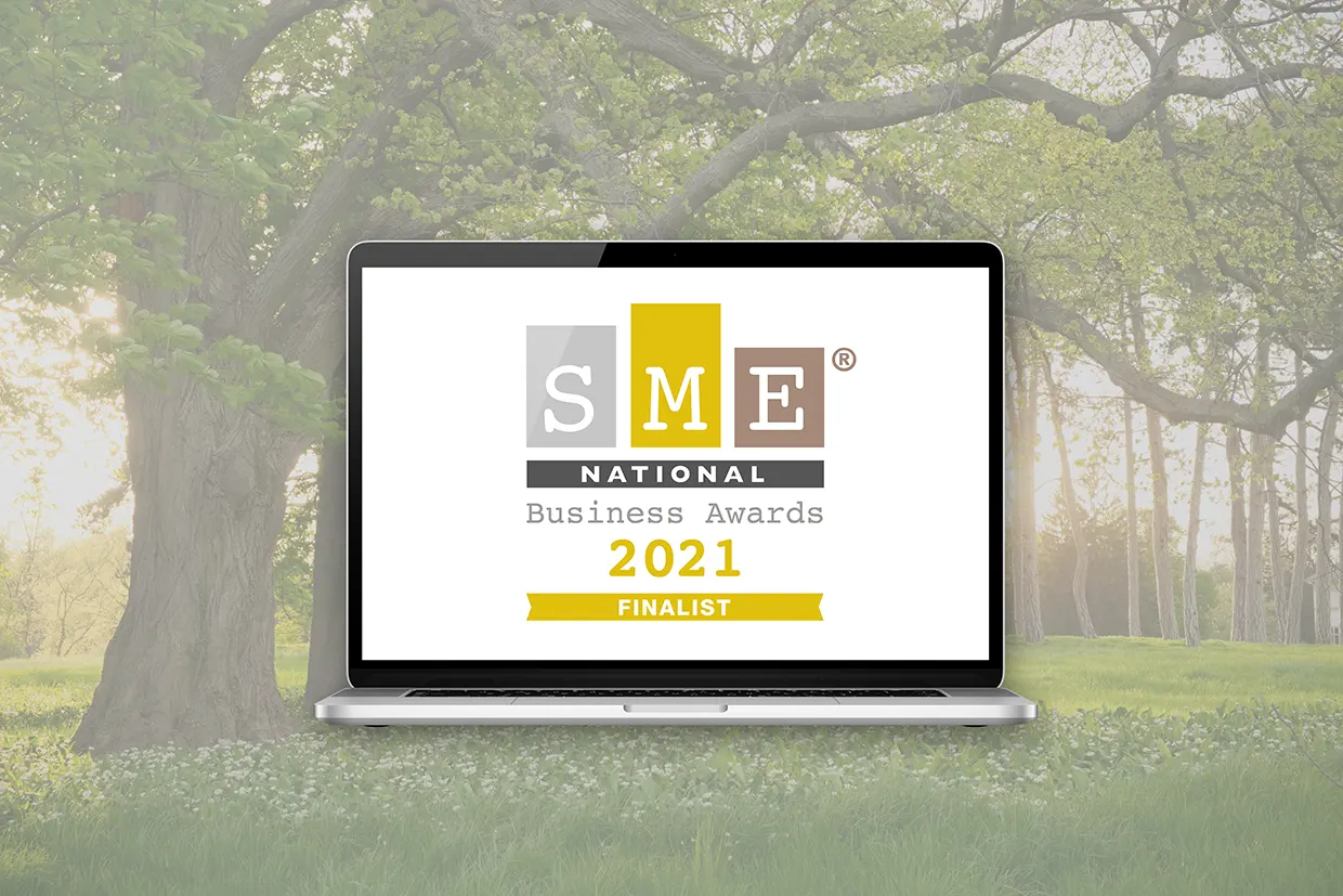Innovation Visual's SME National Business Awards 2021 Finalist Badge for 'Positive Impact' on laptop screen in front of green environment