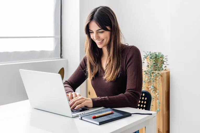 business woman smiles while looking at laptop