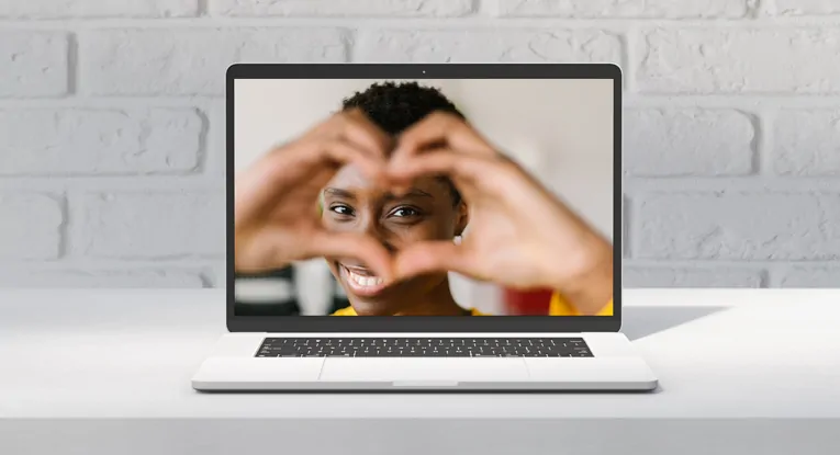 heart hand gesture in front of face promoting helpful content concept on laptop screen
